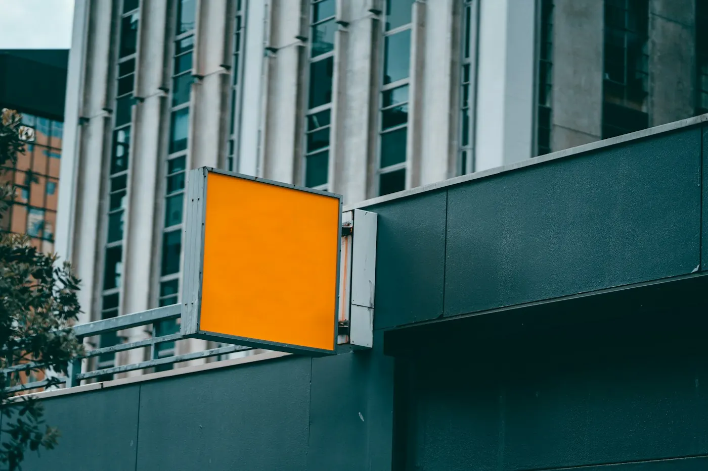 Blank orange illuminated blade sign mounted on a building wall, ready for a business name and logo