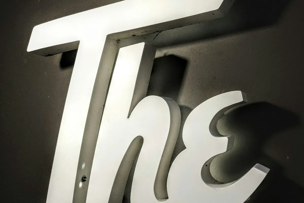Large illuminated white 3D letters mounted on a dark wall, an example of lit signage