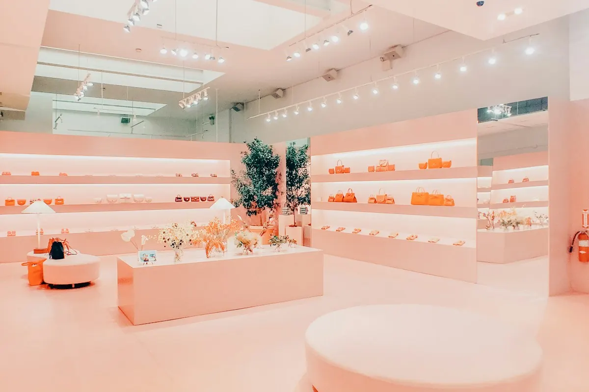 Bright retail store interior with lit wall shelving, a central display table and plants