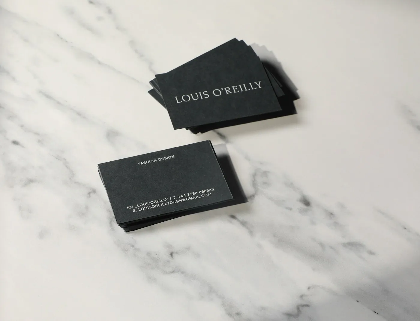 Black business cards with white lettering on a white marble surface, an example of corporate branding stationery